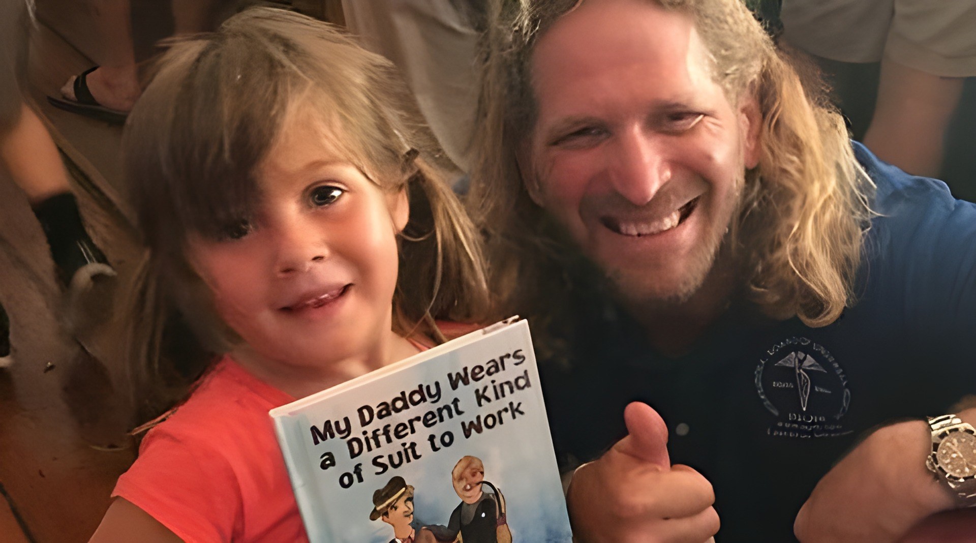 Joseph Dituri with a young reader holding a copy of My Daddy Wears a Different Kind of Suit to Work